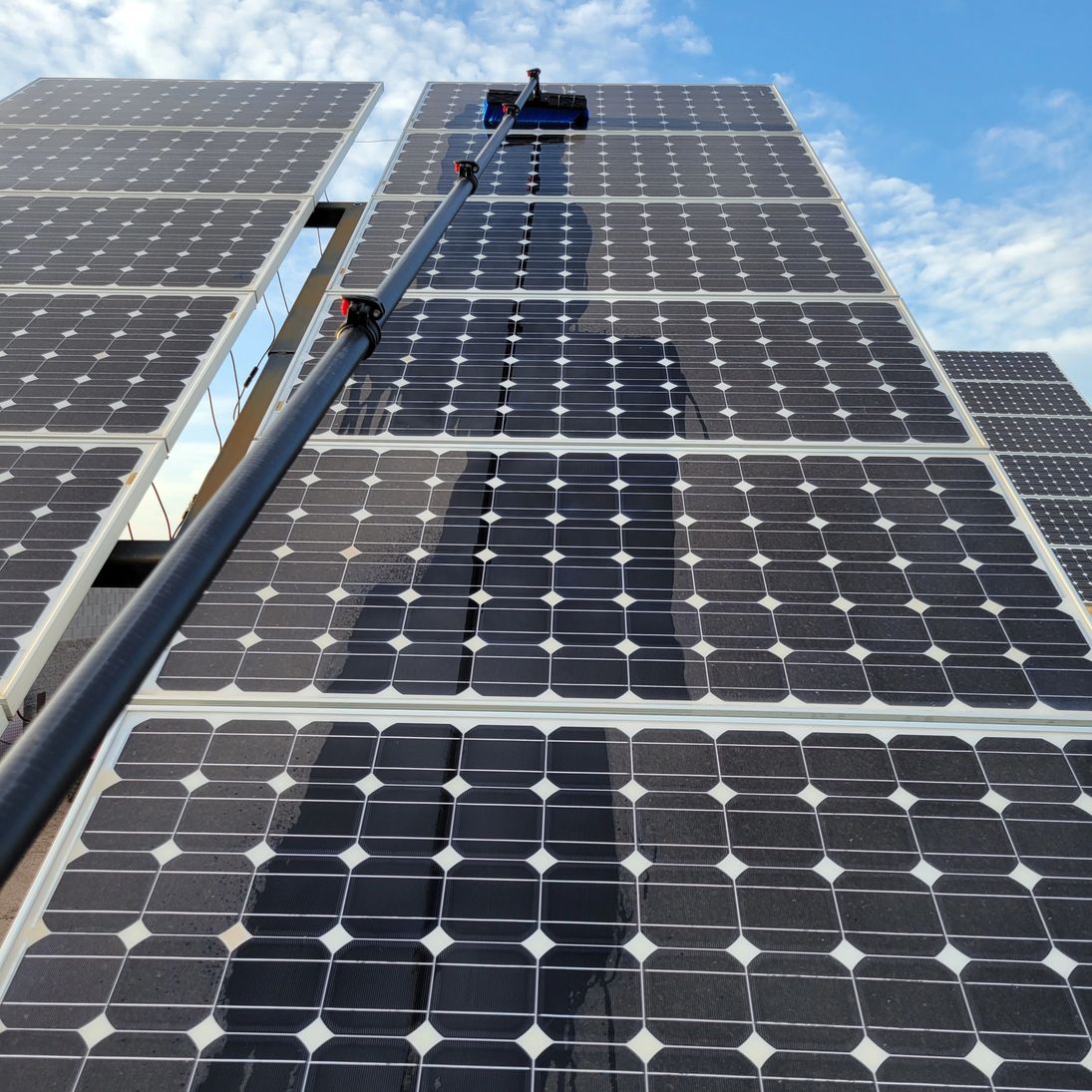 Solar panels being cleaned with a water-fed brush