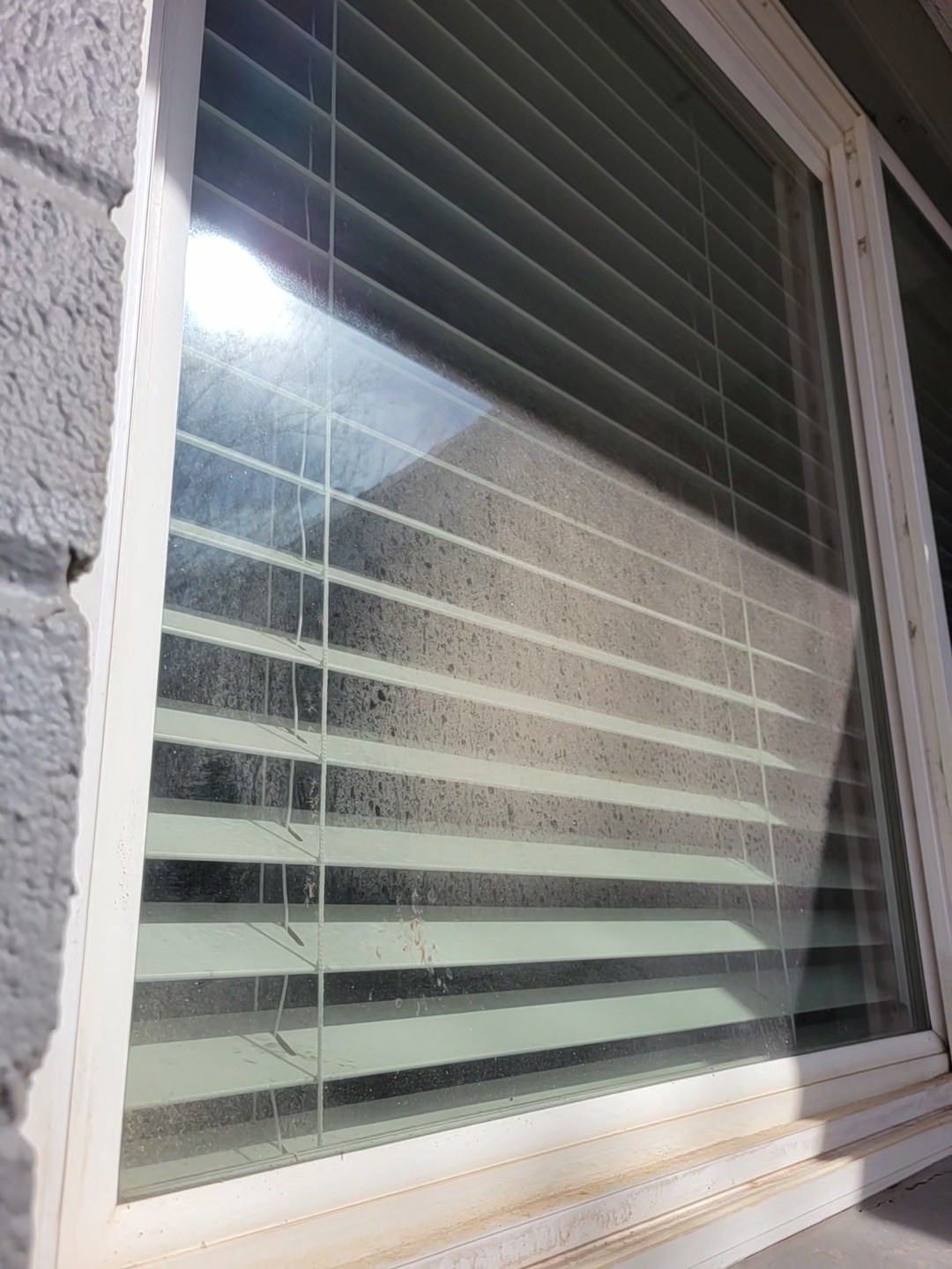 The same residential window before cleaning, with dirt and spots on the glass